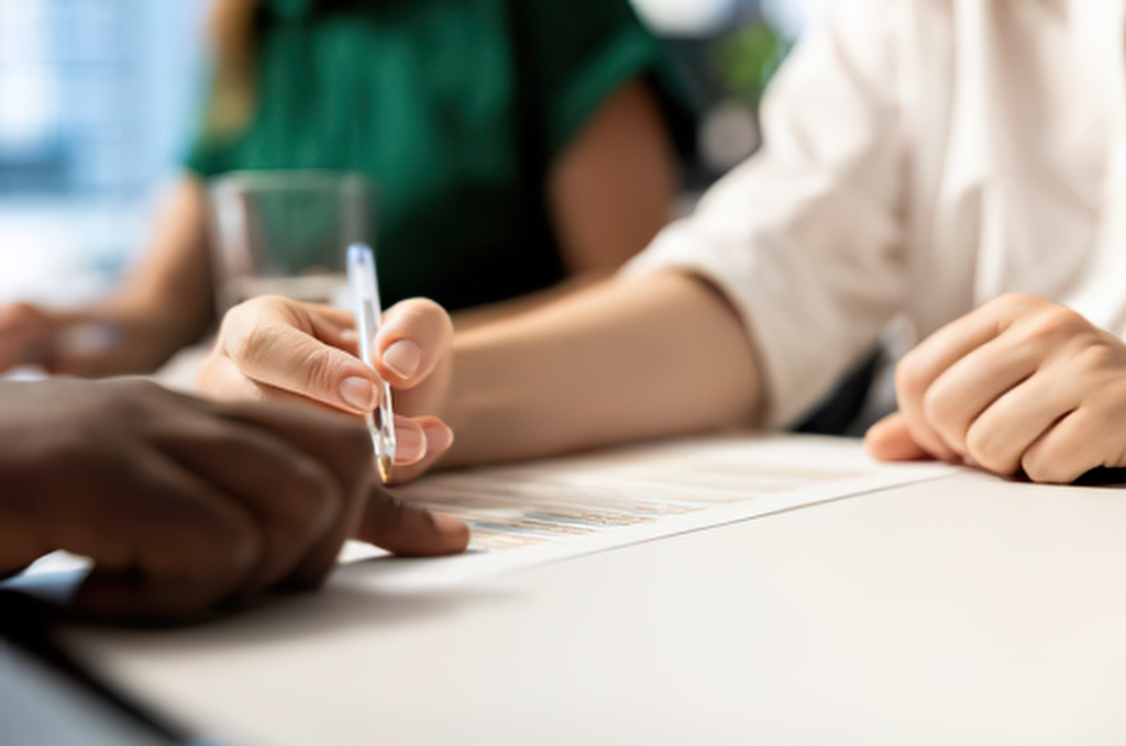 Two people signing a written contract at a desk, one holding a pen